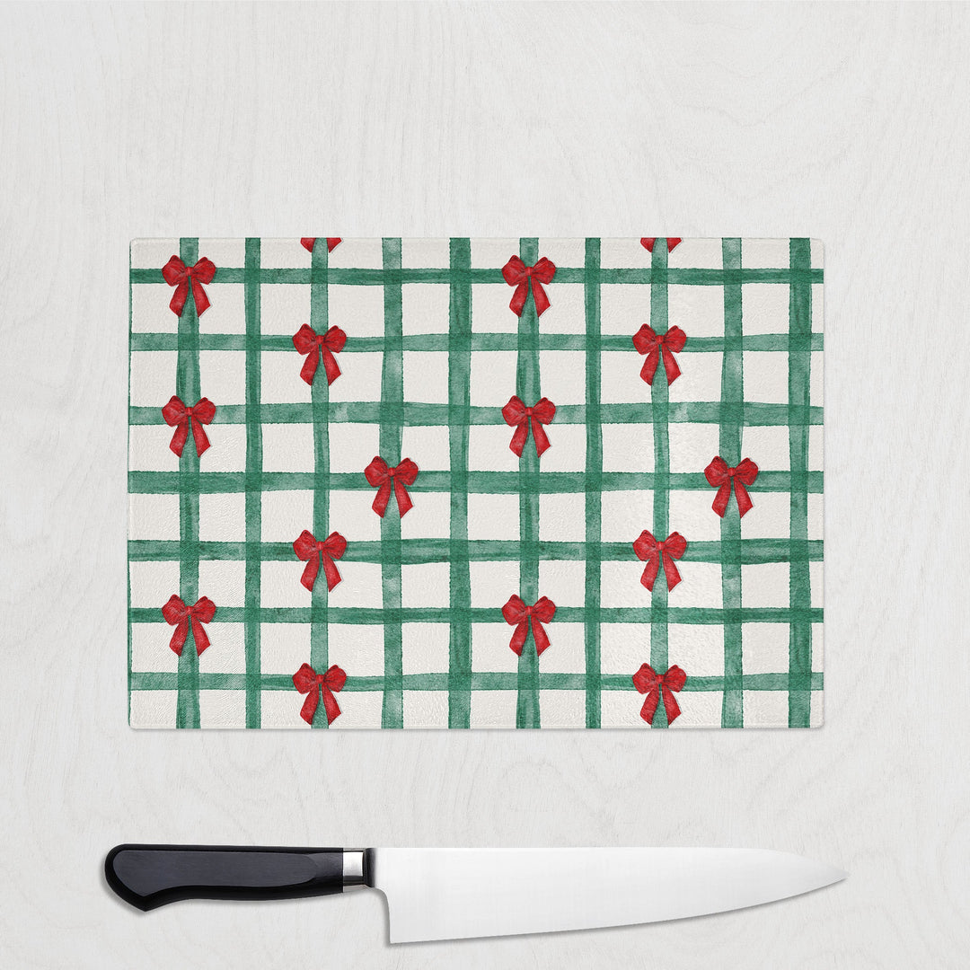 Green plaid cutting board with red bows and a knife on a white background