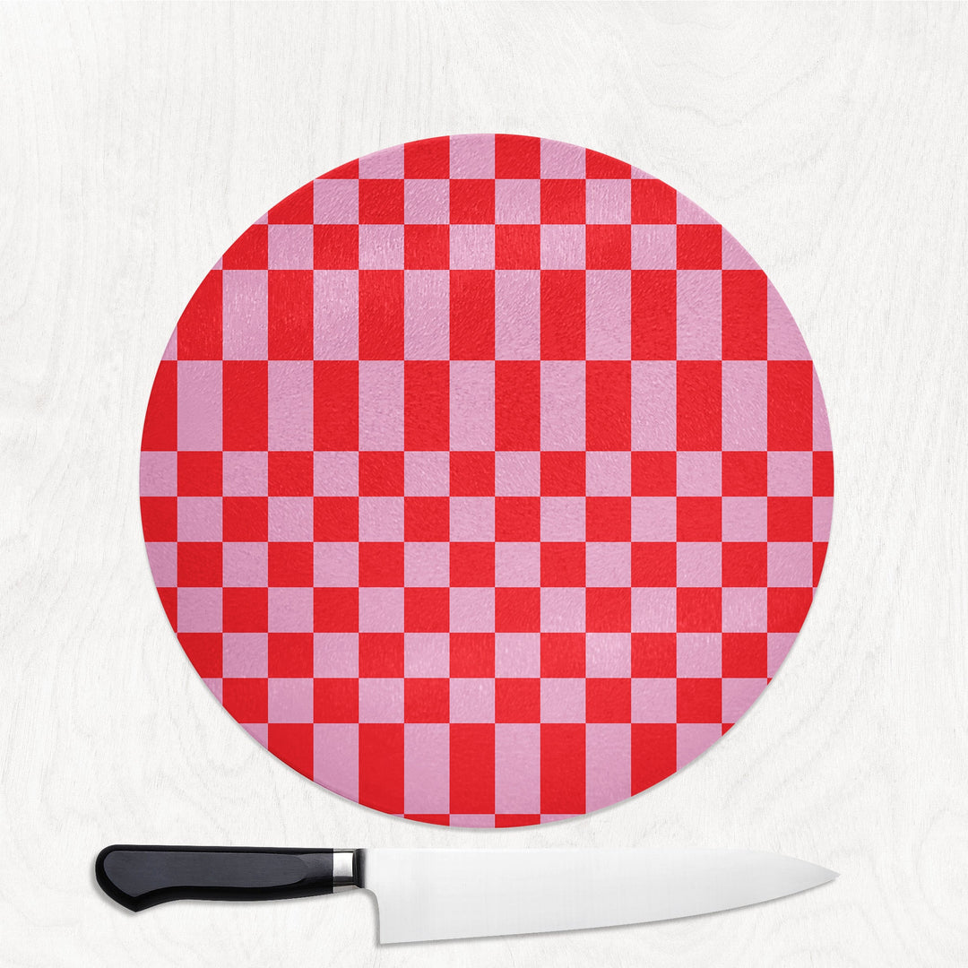 Red and white checkered round cutting board with a knife on a white background