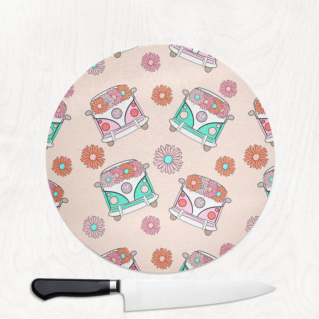 Round cutting board with floral camper design on a white surface with a knife.