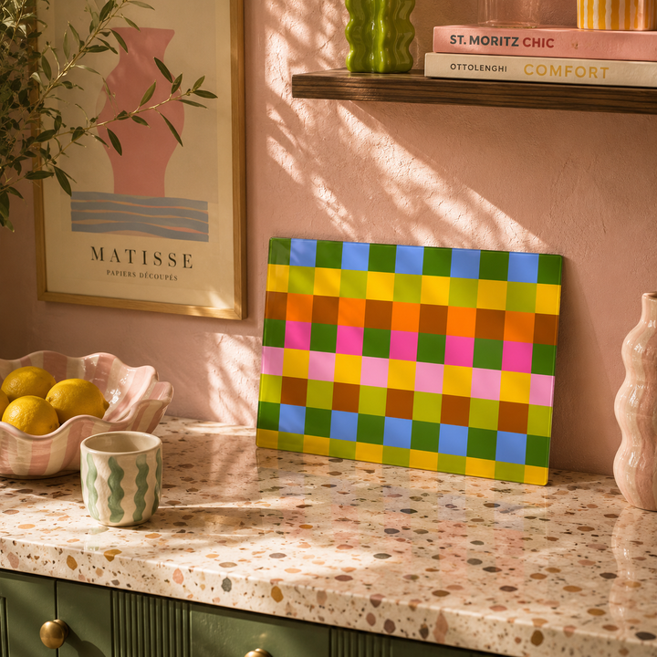 Saffron Plaid Glass Worktop saver leaned up in a kitchen on the work surface, fruit in a bowl with an matisse wall art. 
