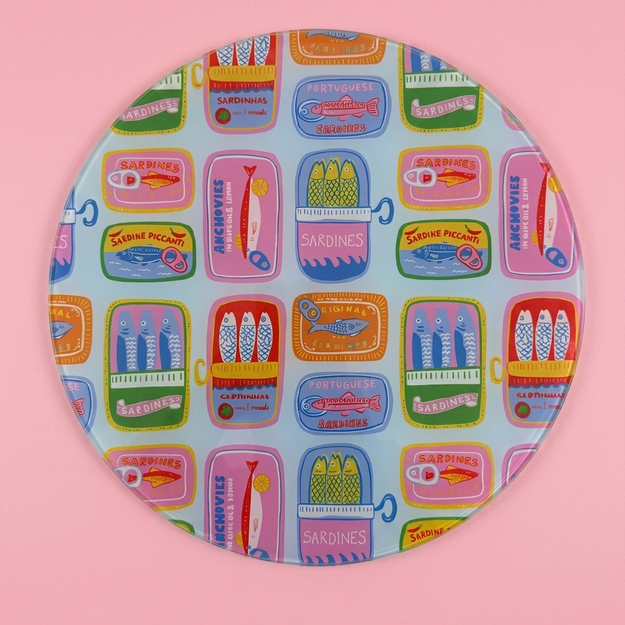 Colourful patterned sardine round glass chopping board on a pink background