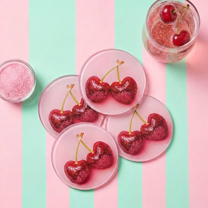 Four Pink Cherry Glass Coasters on a pink and green stripe background with a glass of cherry drink on the side.