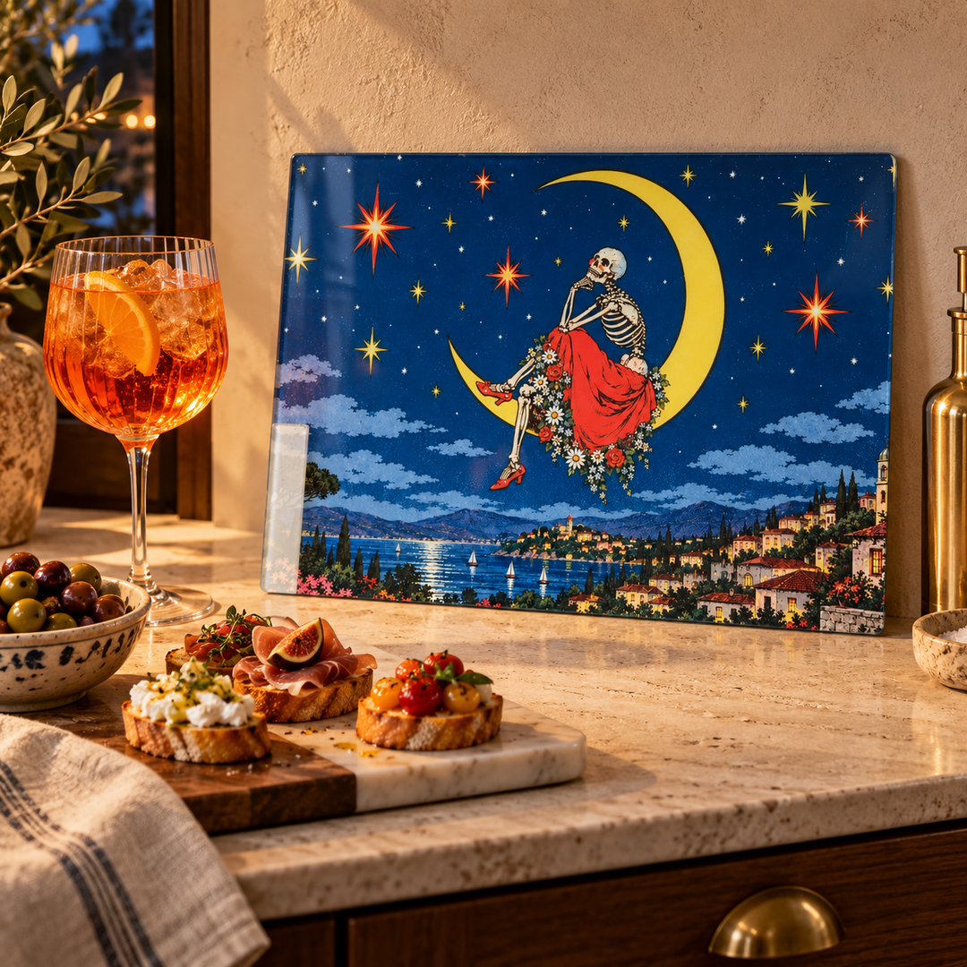 Glass Chopping board on a work surface with a glass of drink and some mini crostinis on and olives in a marble chopping board
