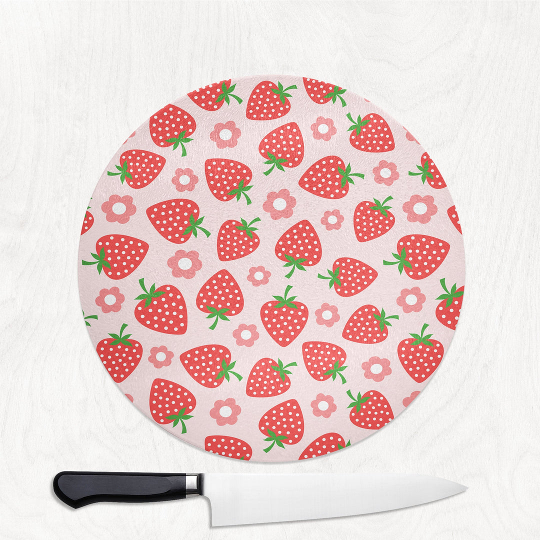 Round cutting board with strawberry pattern and a knife on a white background