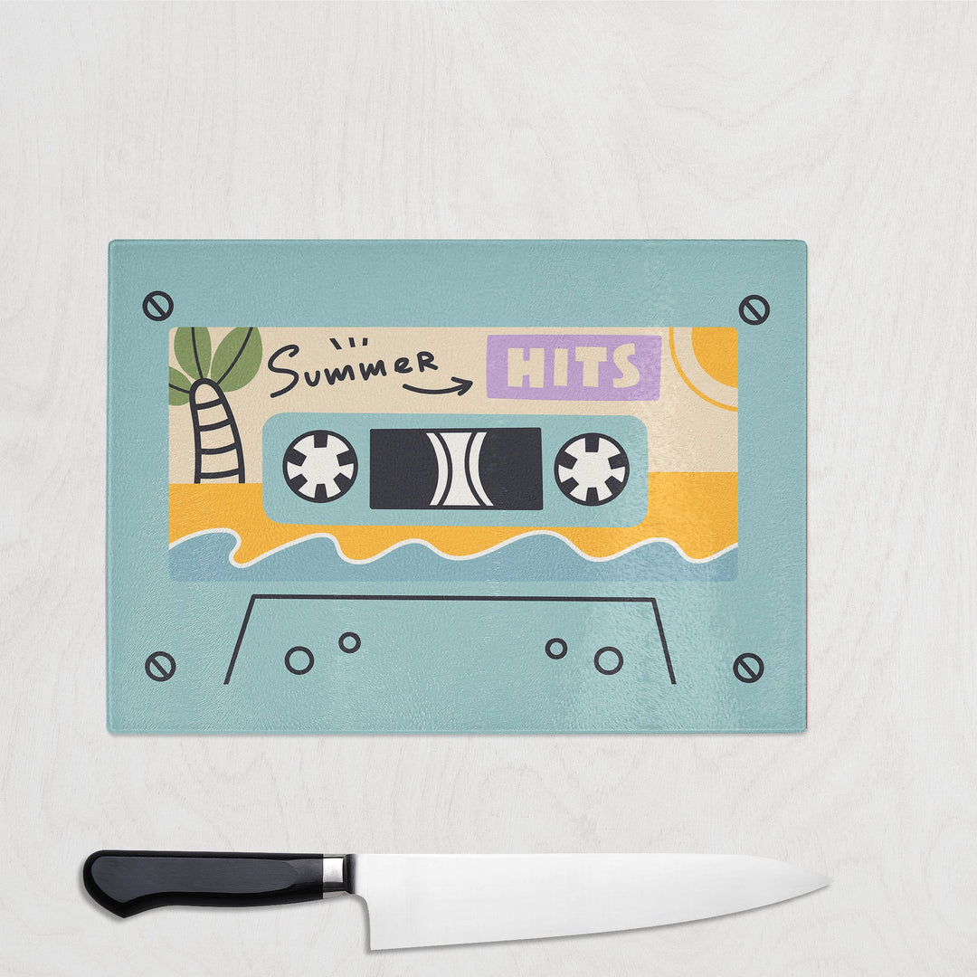 Blue Summer Hits Glass Chopping Board on a white background with a large knife