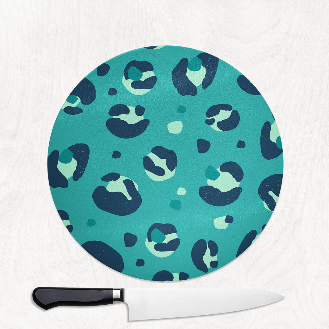 Round teal cutting board with leopard print pattern on a white background
