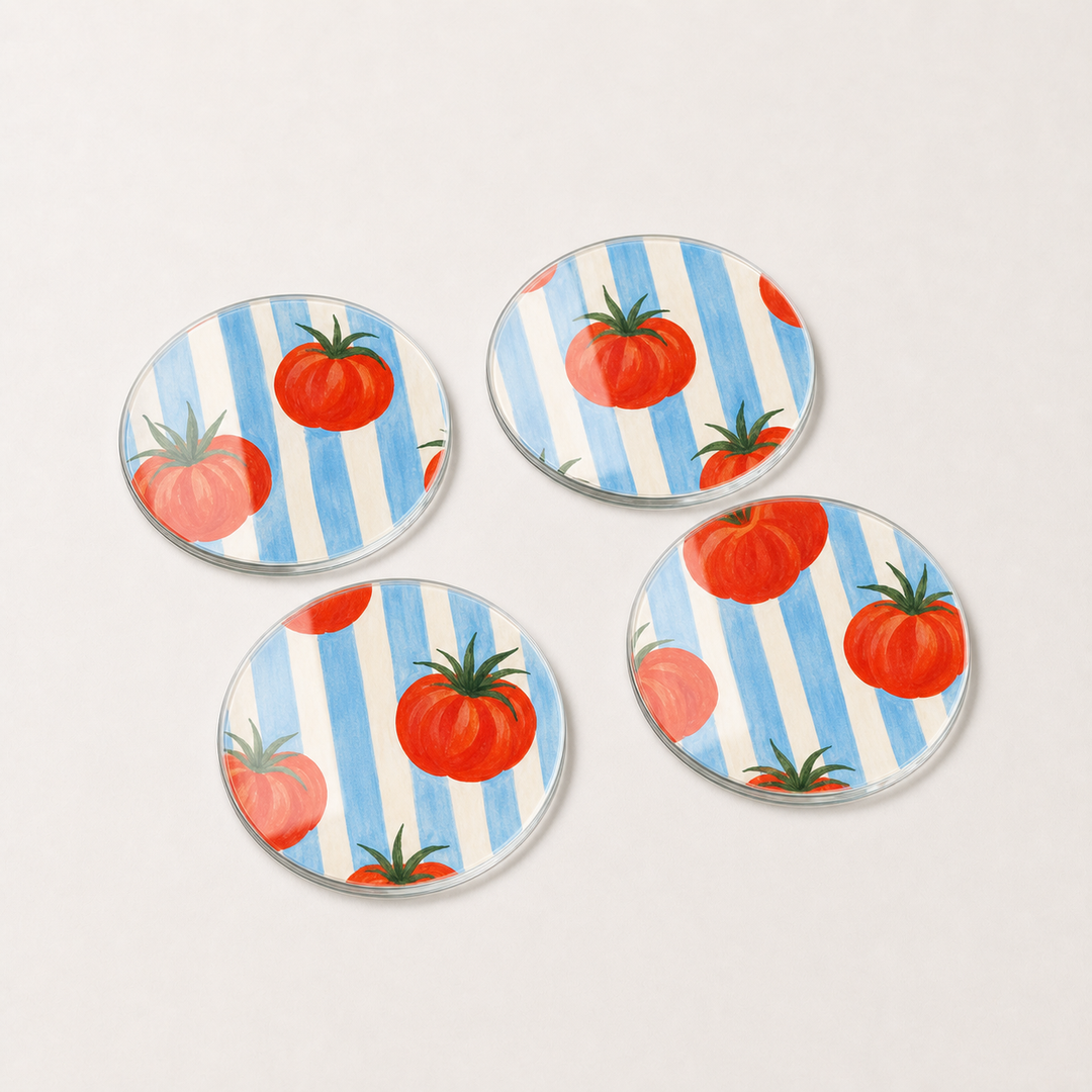 Four glass coasters with tomato design on a blue and white striped background