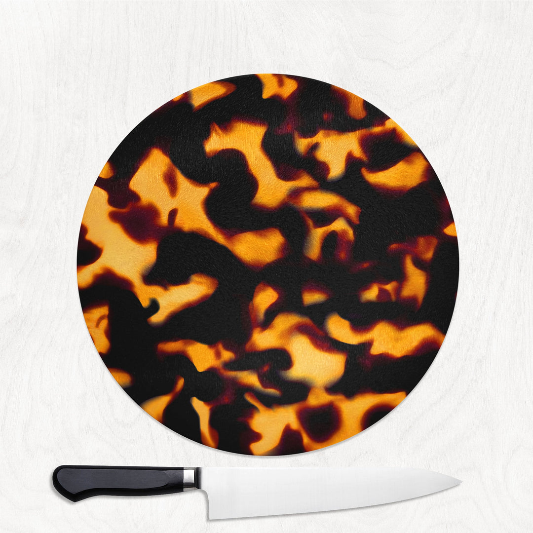 Round tortoiseshell-patterned cutting board with a knife on a white background