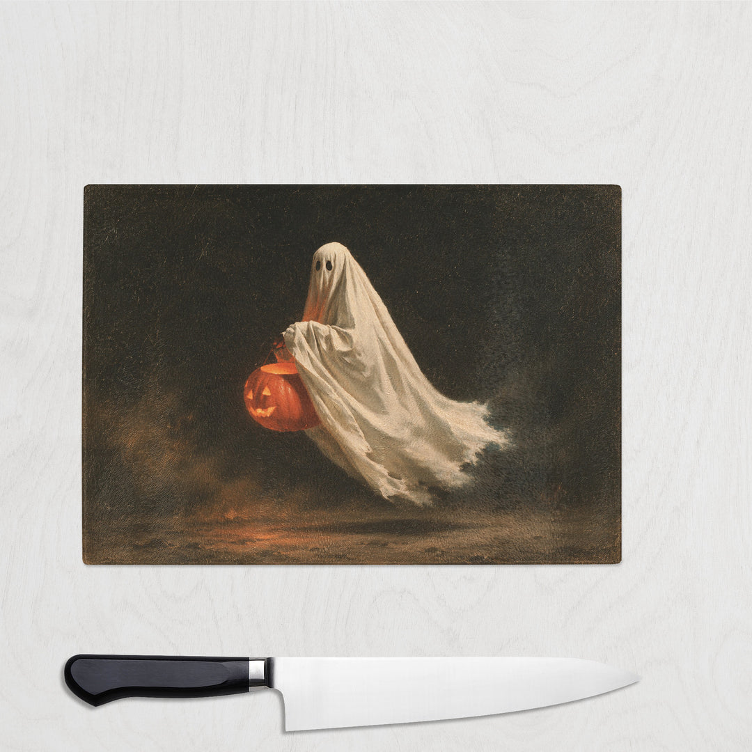 Trick Or Treat Ghost glass chopping board with a small sheet ghost carrying a glowing pumpkin bucket
