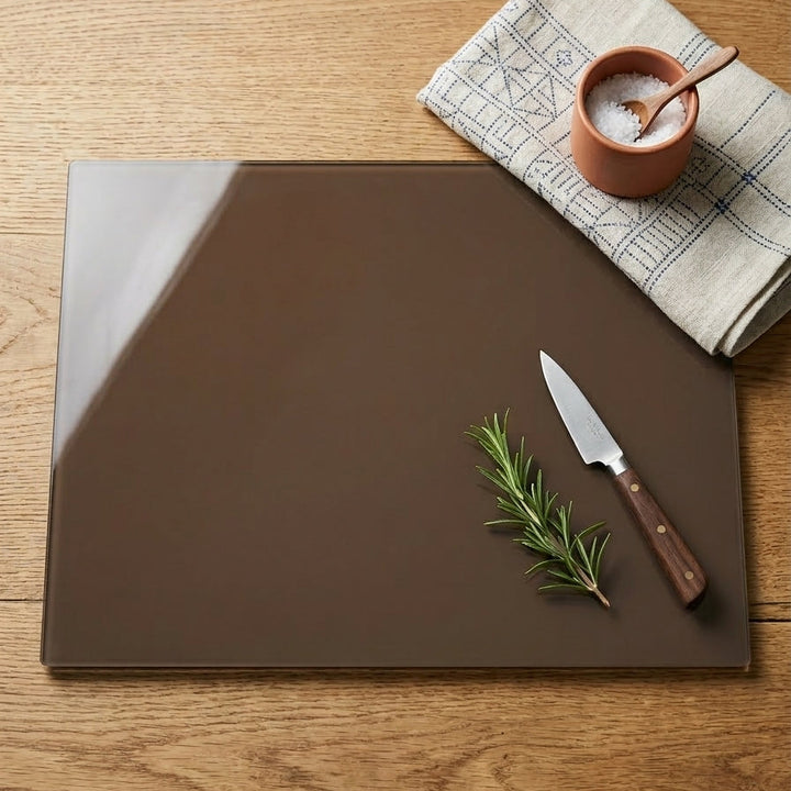 Dark Brown cutting board with a knife and rosemary on a wooden surface