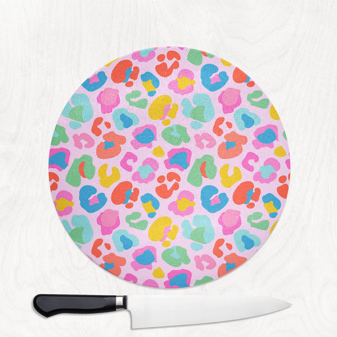 Round cutting board with colorful leopard print pattern on a white background