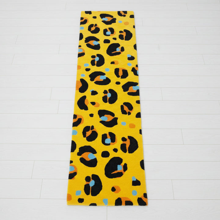 Yellow rug with black and multicolor leopard print on a concrete floor