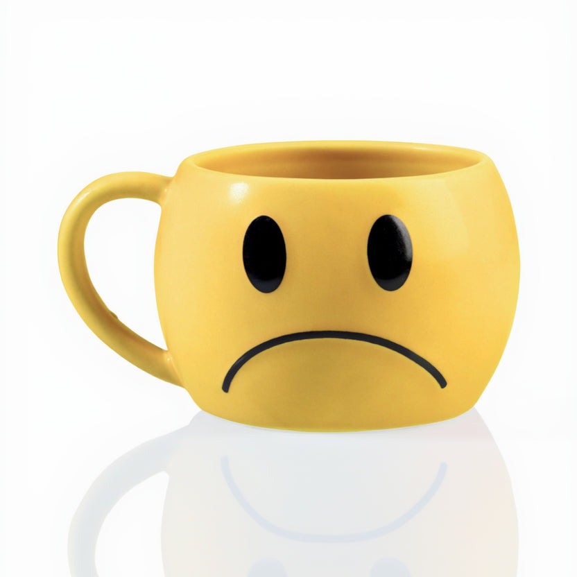 Yellow mug with a sad face design on a white background
