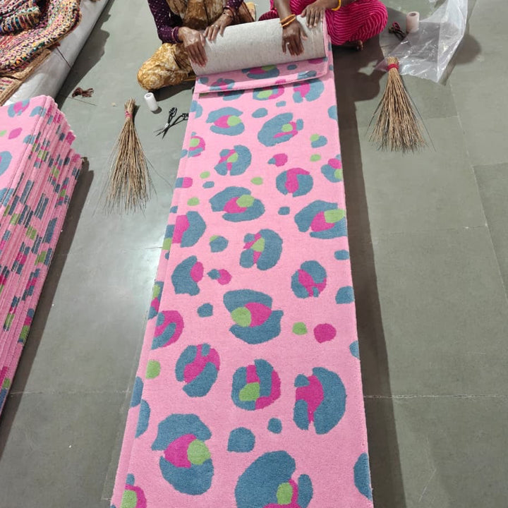 Pink wool leopard print rug on a floor being rolled