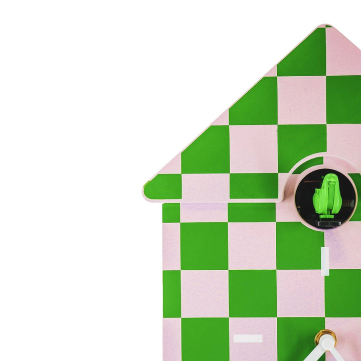 Checkered green and pink house-shaped object with a circular detail on a white background