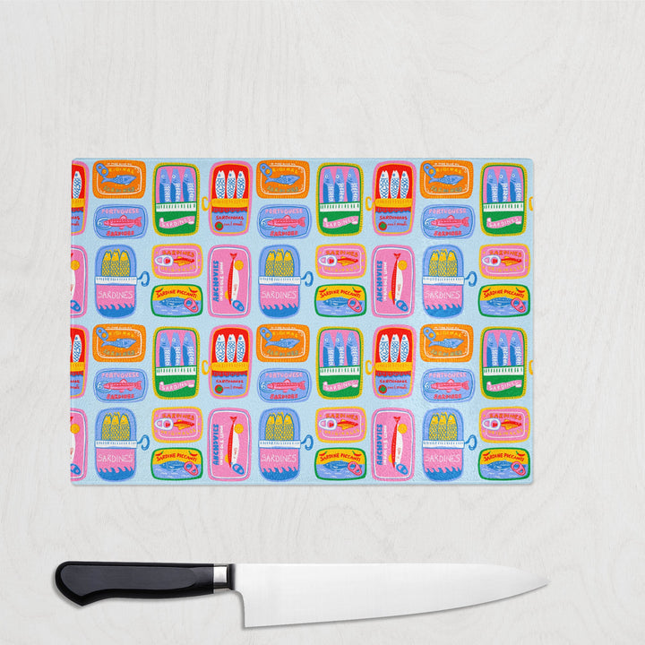 Colourful repeat pattern of illustrated sardine tins printed on a glass chopping board – bold and retro kitchen accessory