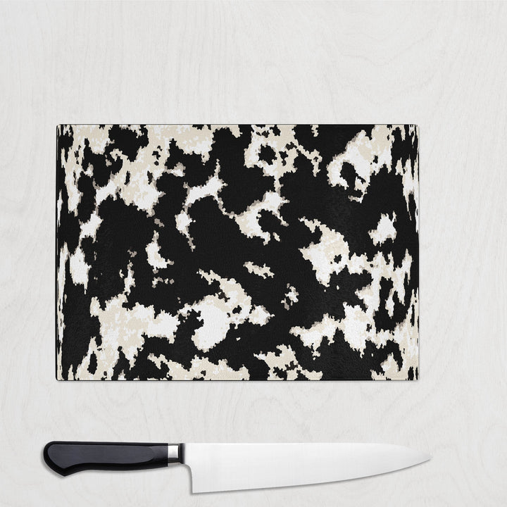 Cow print glass chopping board with black and beige cowhide pattern on a kitchen surface.