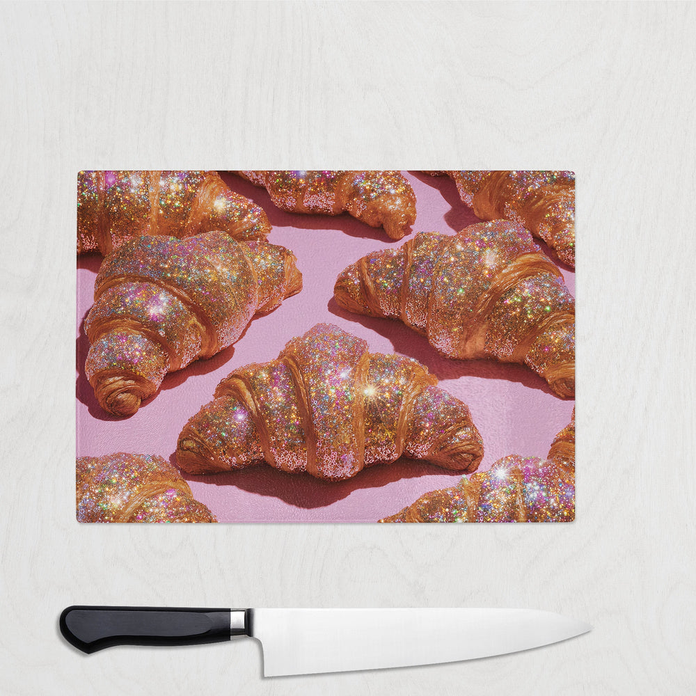 Rainbow glitter-covered croissants on a bright pink background – bold and fun glass chopping board with a pastry design.
