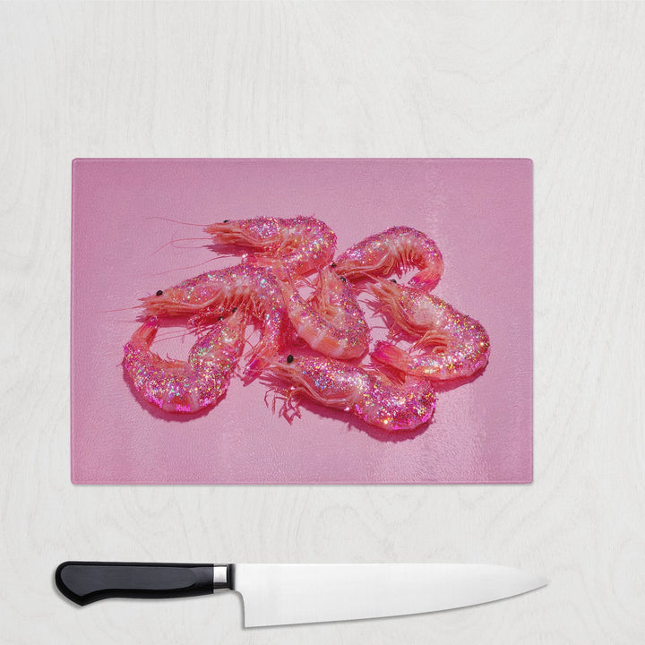 Pink glitter prawns on a bright pink background printed on a glass chopping board – bold, sparkly and fun seafood kitchen accessory.