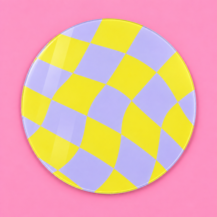 A round glass worktop with a wavy checkerboard pattern in yellow and light purple, set against a solid pink background.