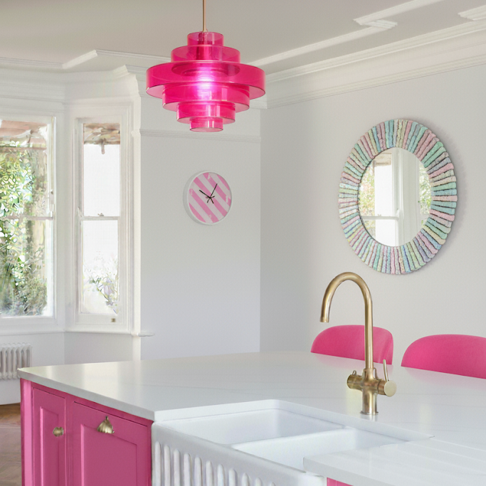Modern kitchen with pink cabinets, a pink pendant light, and colorful mirror.