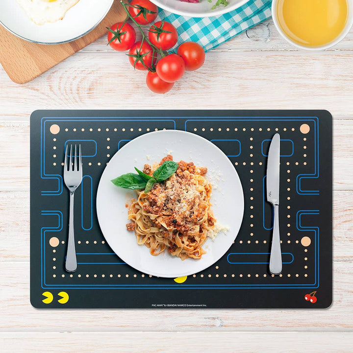 pac man Placemat with a plate of pasta, fork, and knife on a wooden table.