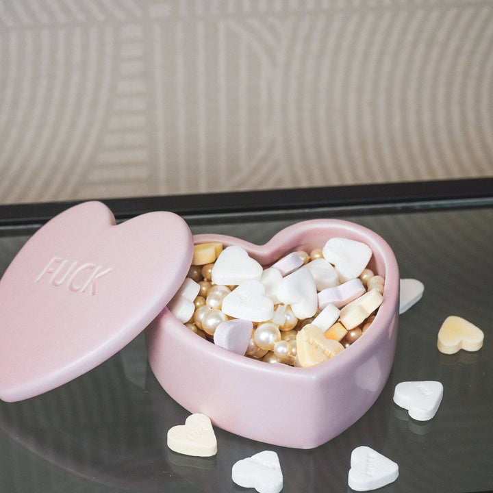Heart-shaped pink ceramic jar with ‘F*CK’ embossed on the lid