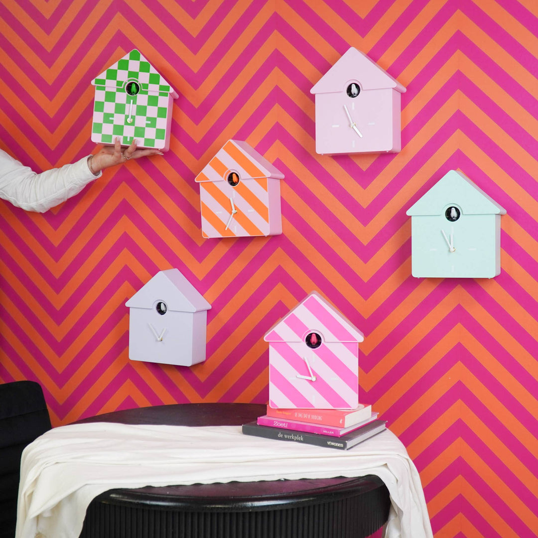 Colorful birdhouse decorations on a wall with a pink and orange zigzag pattern.