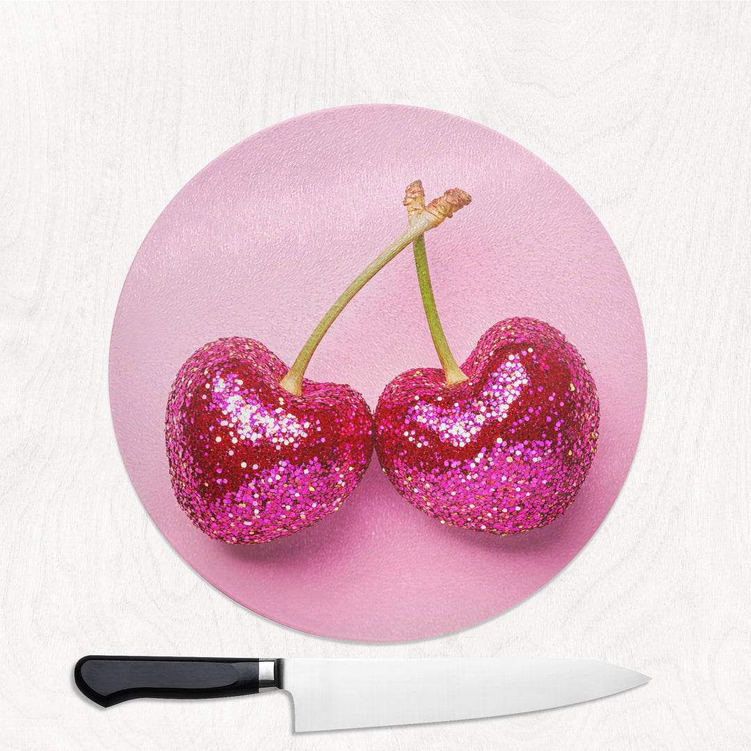 Pink round glass chopping board with glitter sequin cherry design on a soft pink background