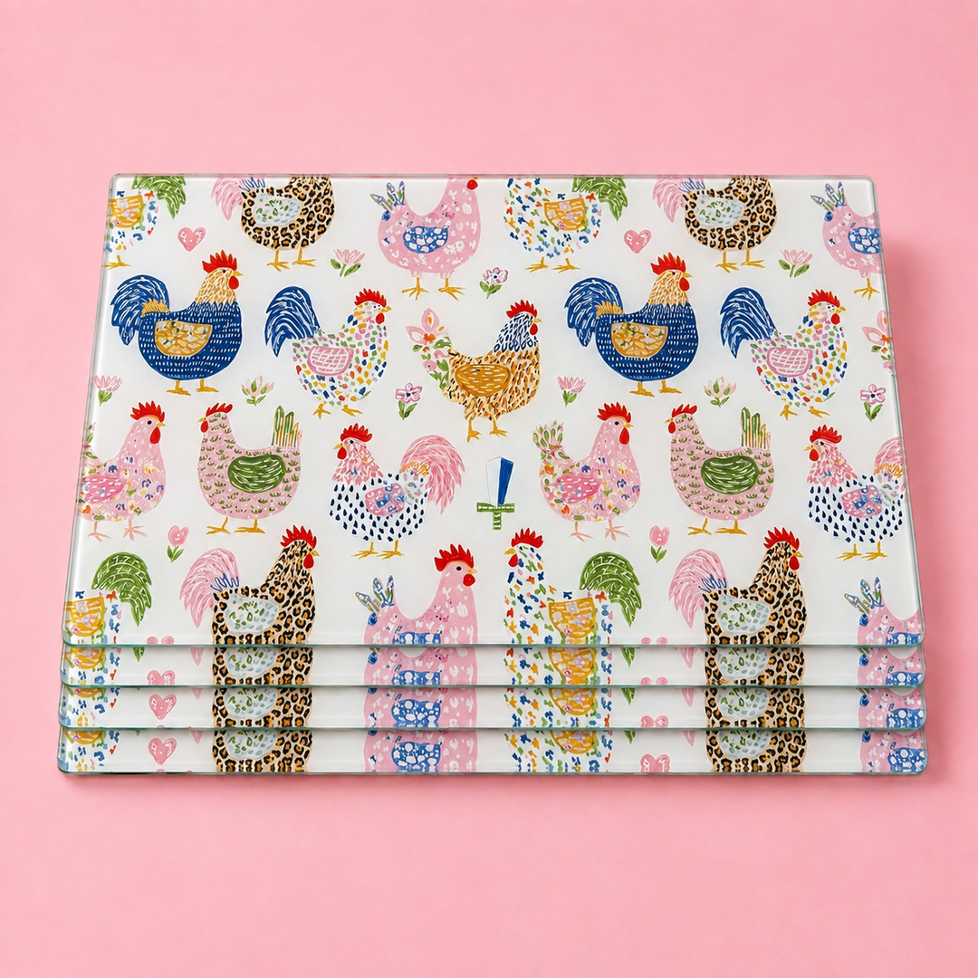 Stack of Yililo Chicken Dance glass placemats, printed with a flock of cheerful hand-drawn chickens.