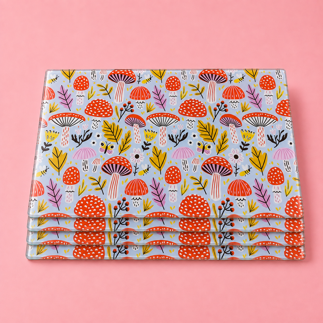 Stack of Yililo Mushroom Magic glass placemats, a woodland design of toadstools, leaves, bees and butterflies.