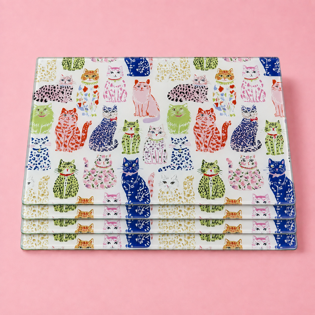 Stack of Yililo Spotty Cats glass placemats, covered in playful spotty and leopard-print cats.