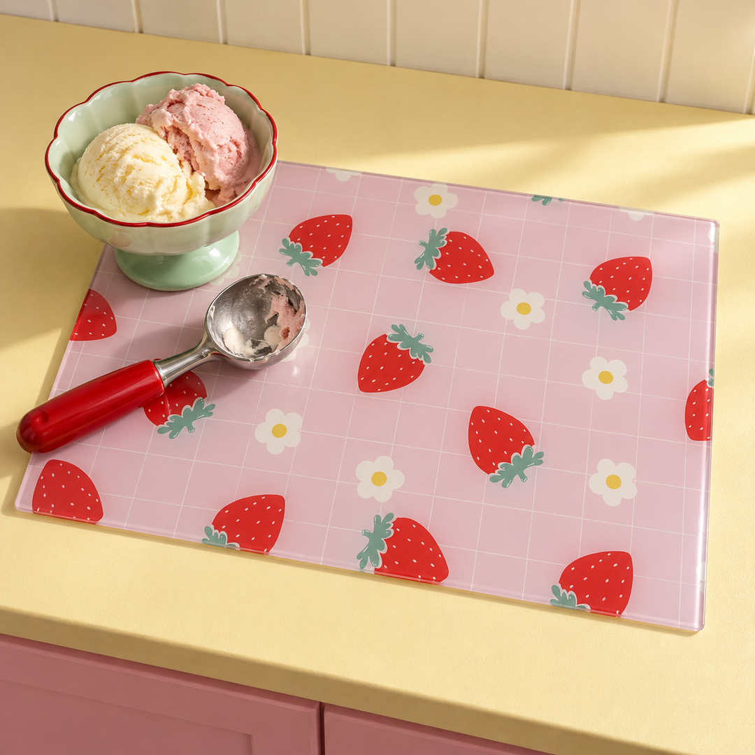 Strawberry Check glass chopping board worktop saver on a yellow counter with a bowl of strawberry and vanilla ice cream and a red ice cream scoop